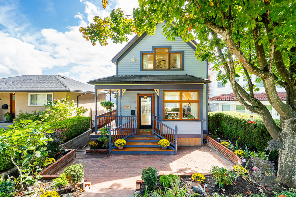 A beautifully preserved 100+ year-old blue heritage home in New Westminster, framed by lush greenery and a brick walkway. This historic home, once a creative haven for a Juno-nominated recording artist, set the stage for a rock star sale.