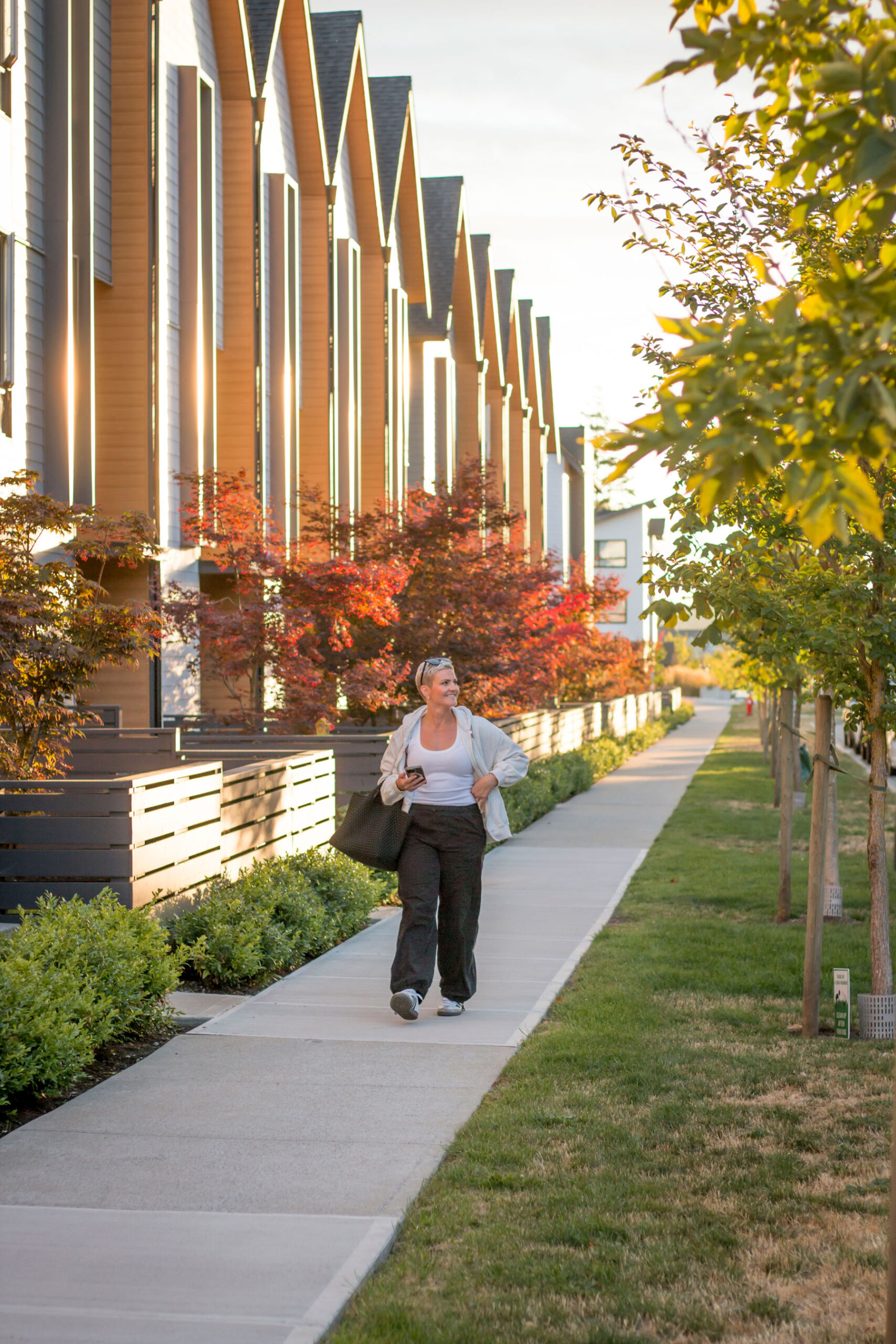 Amy Dewaele walks through the vibrant Grandview neighbourhood in South Surrey, surrounded by modern townhomes, lush greenery, and warm evening light.